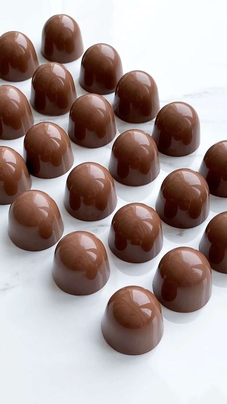 Glossy milk chocolate dome bonbons on white marble